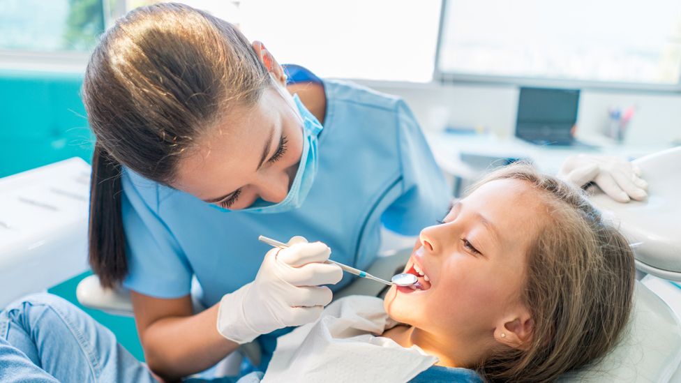 دندانپزشک عمومی در حال چگاپ یک دختربچه کوچک