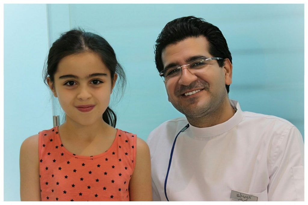 تصویر دکتر درویش پور و یکی از مراجعان خردسالی که برای درمان ارتودنسی مراجعه کرده بود