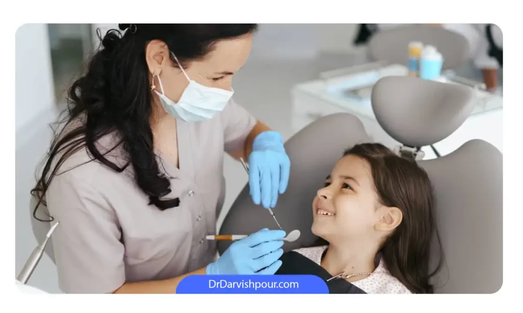 یک دندانپزشک کودکان که در حال ویزیت بیمار خردسال خود است